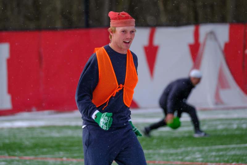 a man wearing an orange vest and gloves on a field