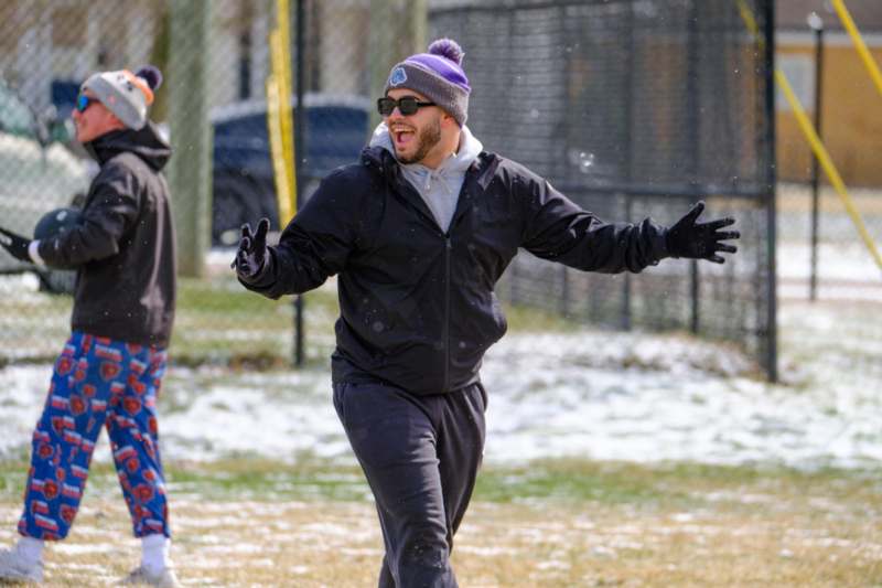a man in a hat and sunglasses running in the snow
