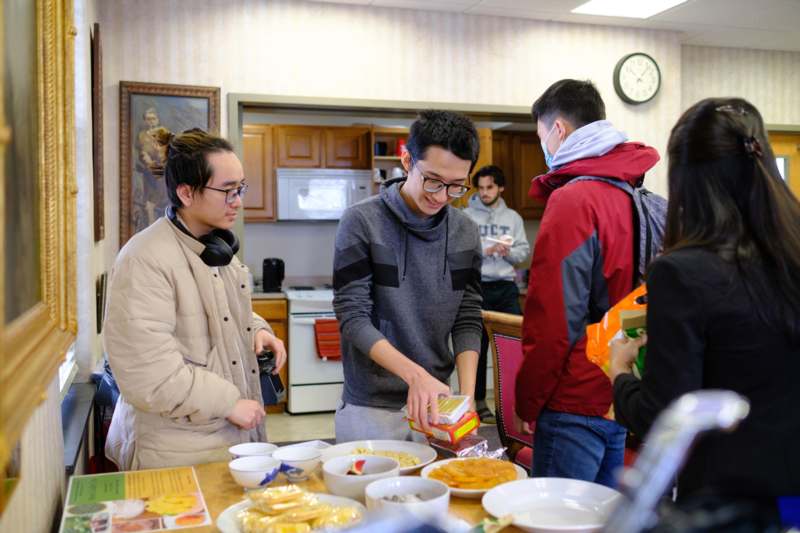 a group of people standing around a table with food