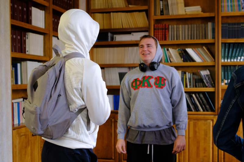 a man wearing a backpack and standing next to a person wearing headphones