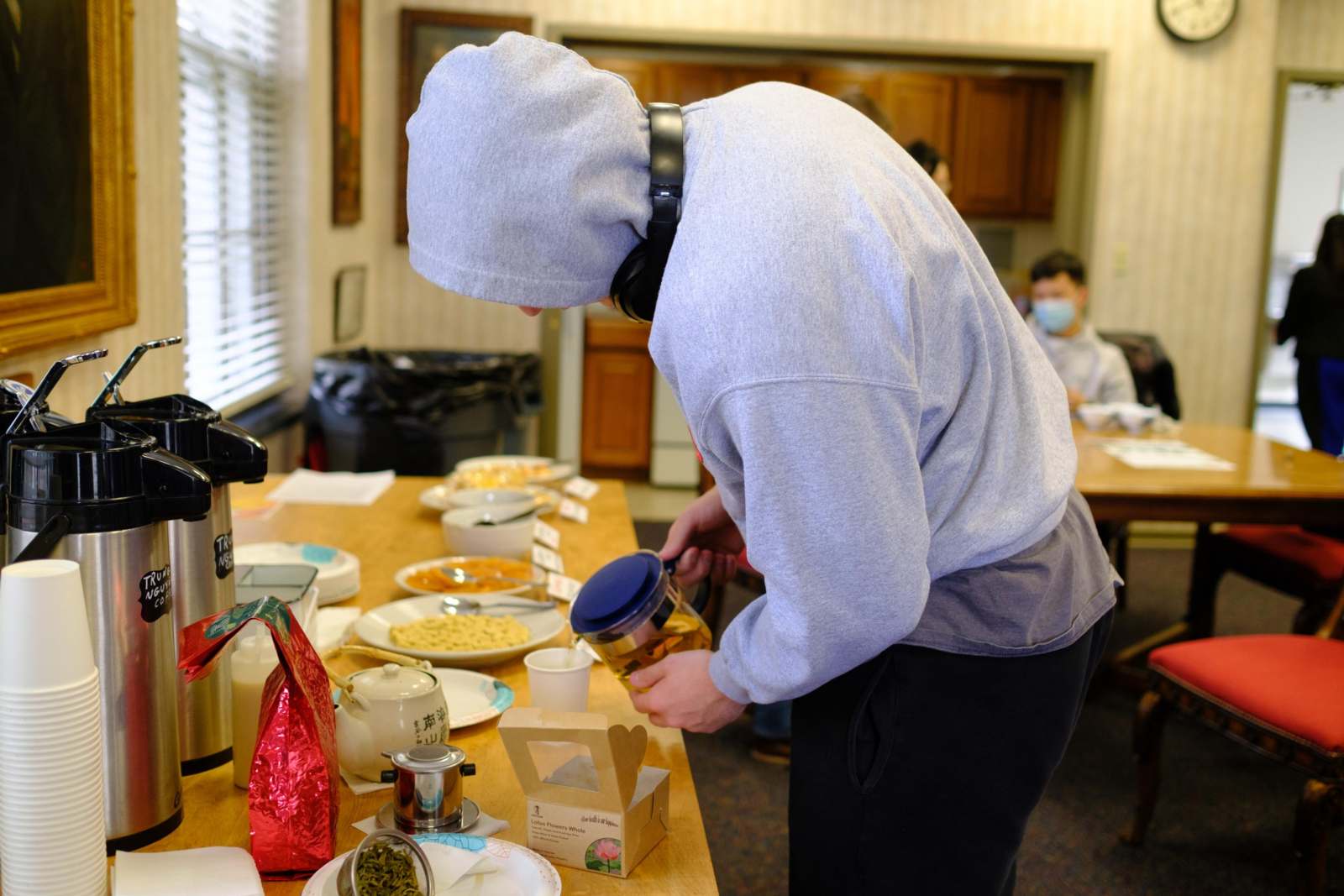 a person in a hoodie pouring food into a container