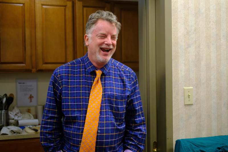a man in a blue shirt and orange tie laughing