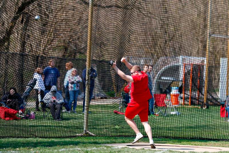 a man in red holding a bat in front of a net