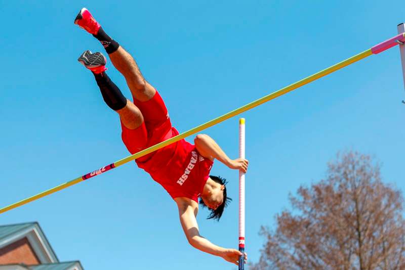 a man in red shorts jumping over a bar