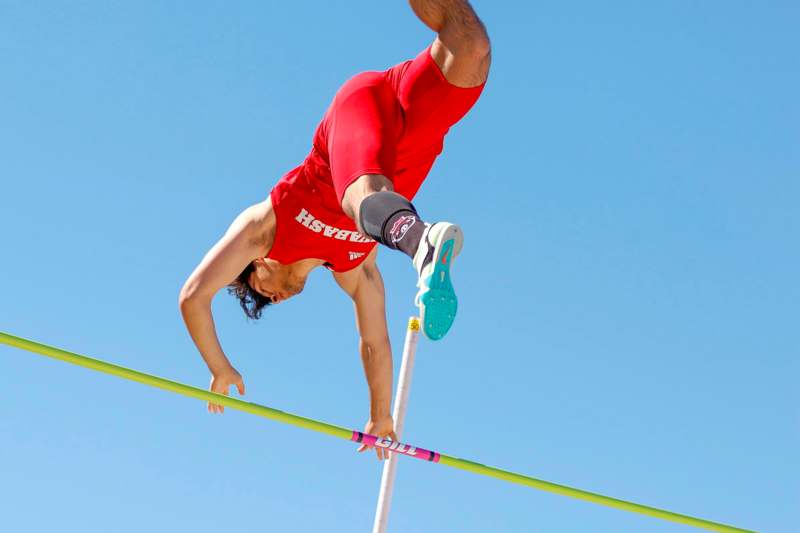 a man in red shorts and a red shirt doing a high jump