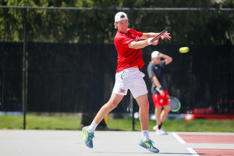 a man in a red shirt and white shorts playing tennis