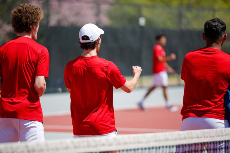 a group of men in red shirts on a tennis court