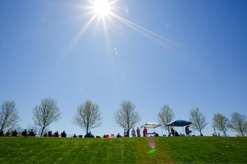 a group of people on a grassy hill under the sun