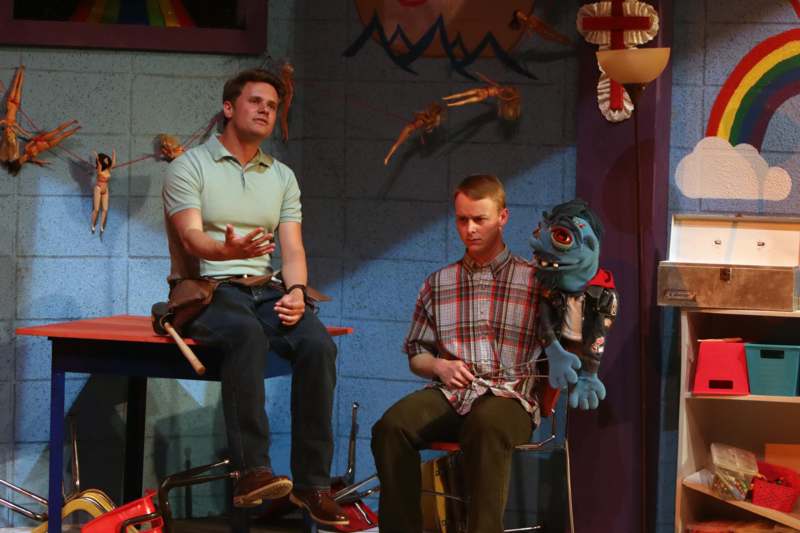 a man sitting on a chair with a puppet on his lap