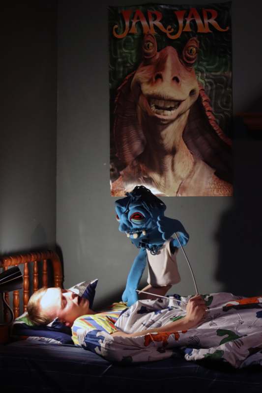 a person in bed with a blue puppet