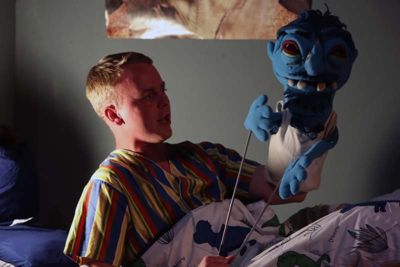 a man in a hospital bed with a blue puppet