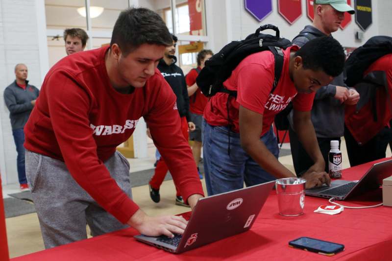 a group of men in red shirts using laptops