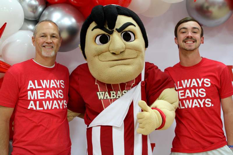 two men posing with a mascot