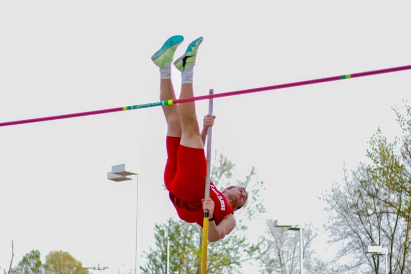a man in red shorts holding a bar over a pole