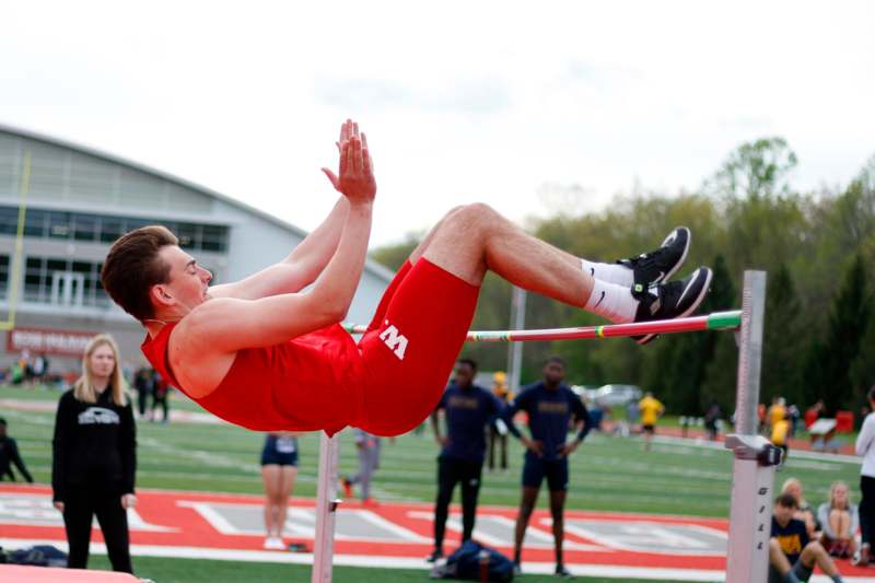 a man in red shorts doing high jump on a pole