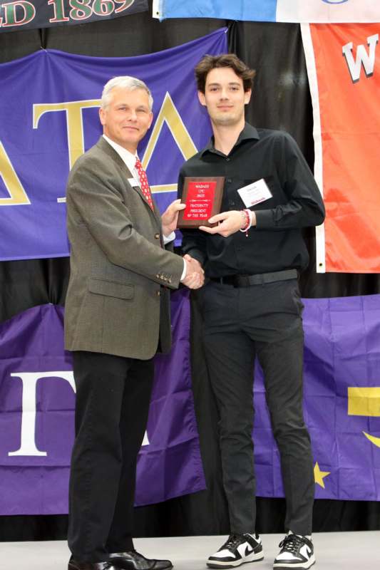 a man shaking hands with a man holding a plaque