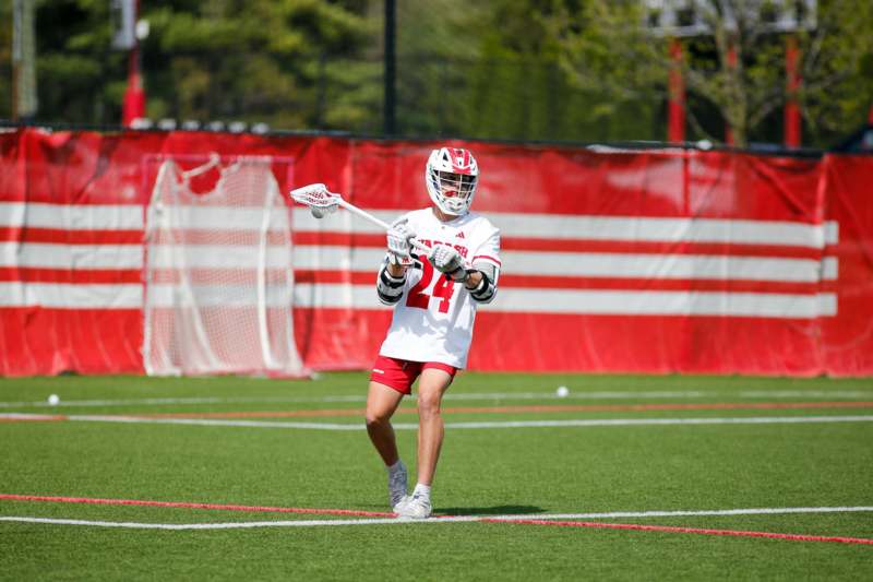 a person in a white uniform holding a lacrosse stick