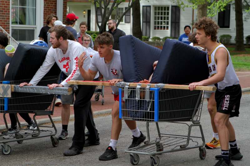 a group of men pushing shopping carts with mattresses