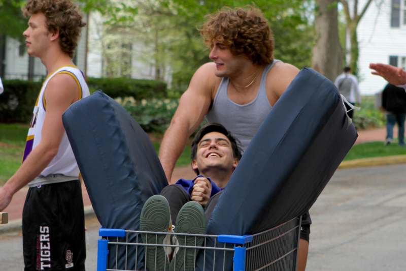 a man riding in a shopping cart with two men