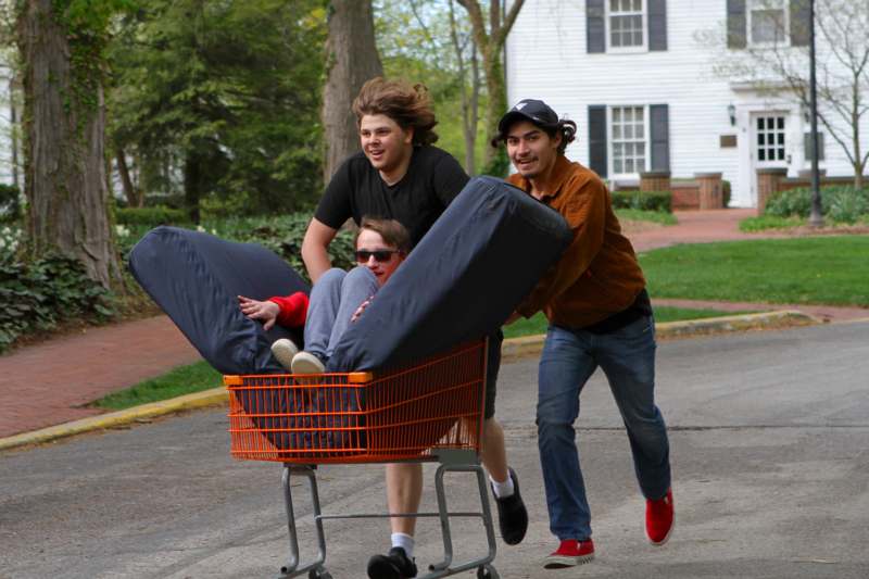 a group of men pushing a shopping cart with a person in it