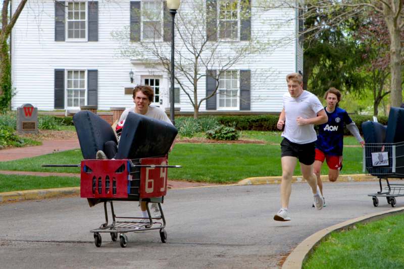 a group of men running on a street with a shopping cart