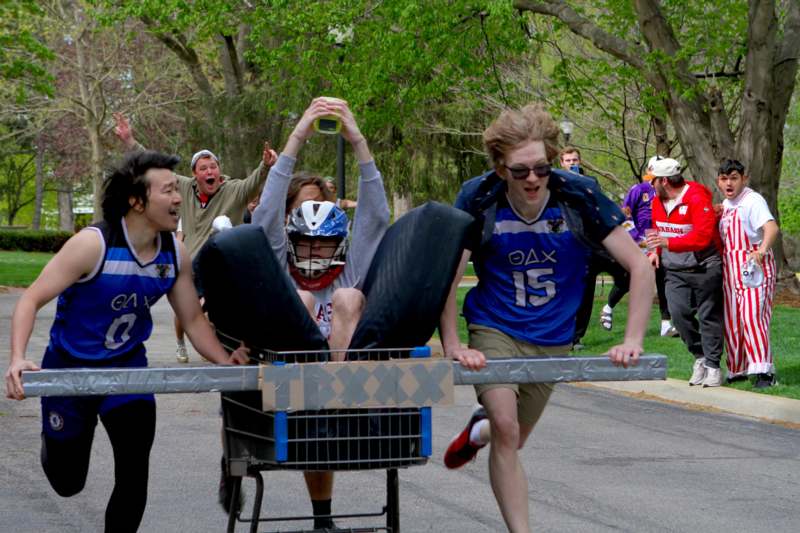 a group of people pushing a cart with a person on it