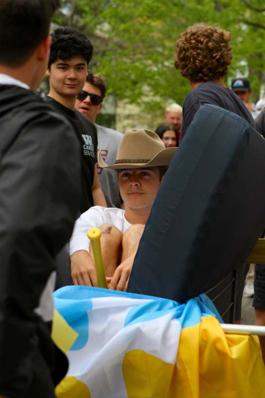 a man in a cowboy hat sitting in a cart with other people around him