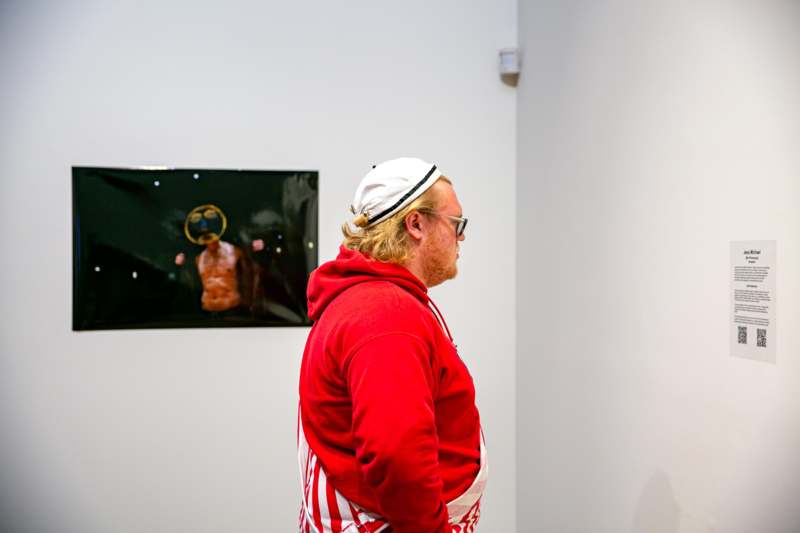a man in a red and white striped sweatshirt and white hat looking at a painting