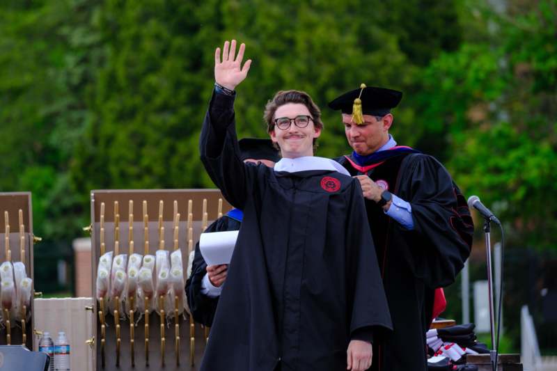 a man in a graduation gown waving