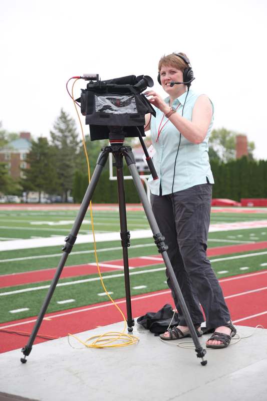 a woman with headphones on standing on a stand with a camera