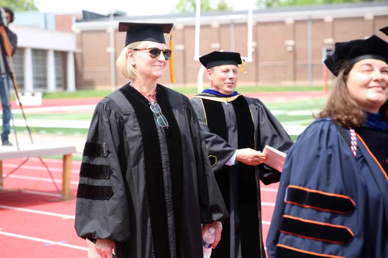 a woman in a graduation gown and cap standing on a track