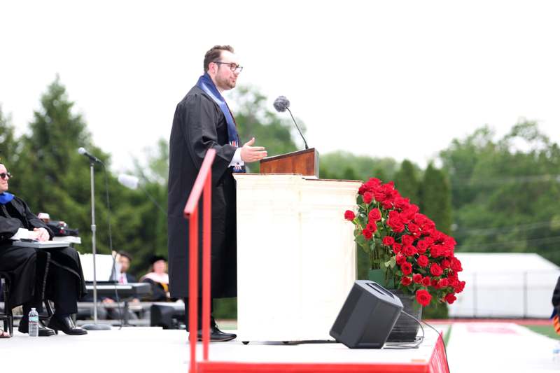 a man standing at a podium with a microphone and flowers