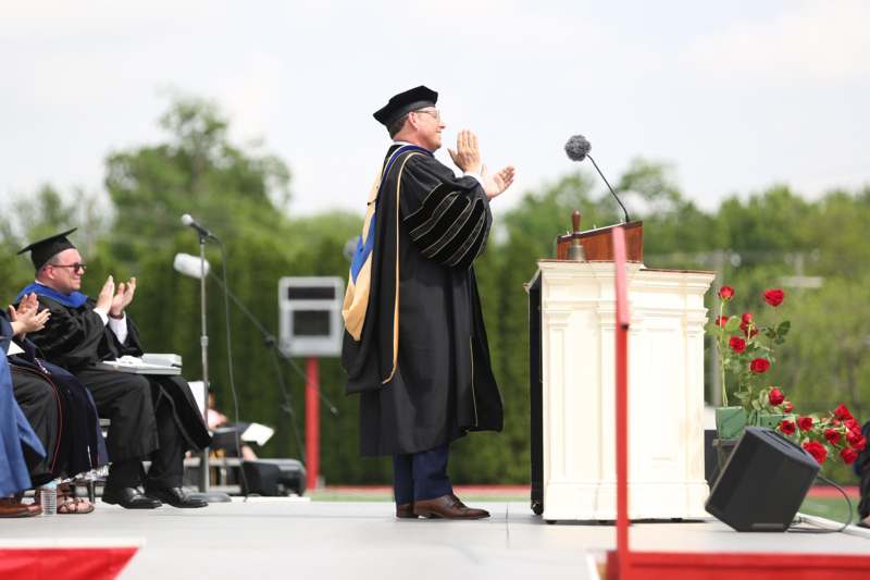 a man in a graduation gown standing at a podium