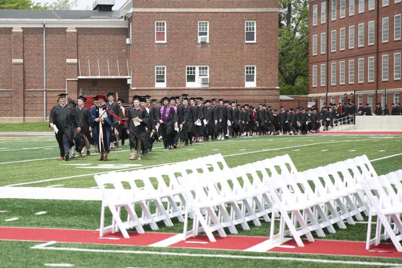 a group of people in graduation gowns walking on a football field