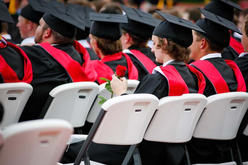 a group of people in graduation gowns and cap sitting in chairs
