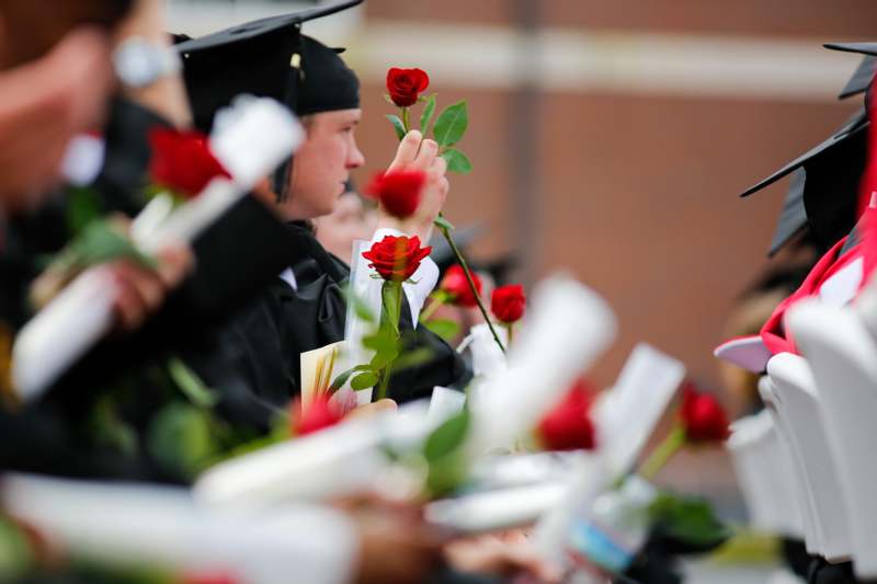 a group of people in graduation gowns holding roses