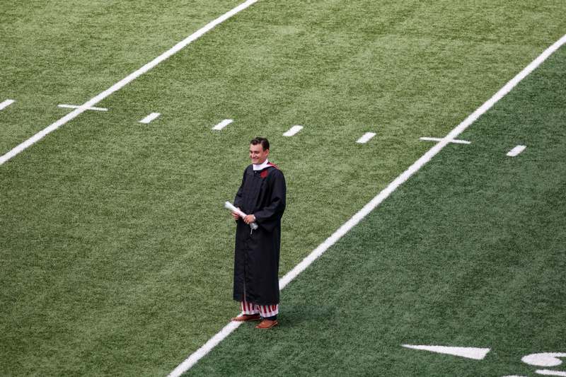 a man in a graduation gown standing on a football field