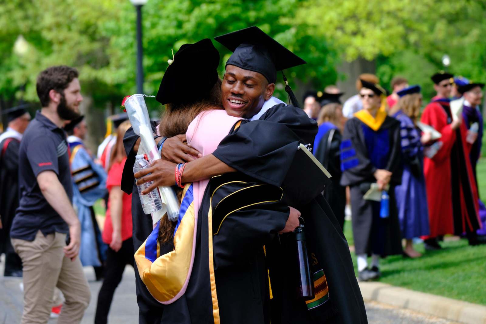 a man in cap and gown hugging a woman