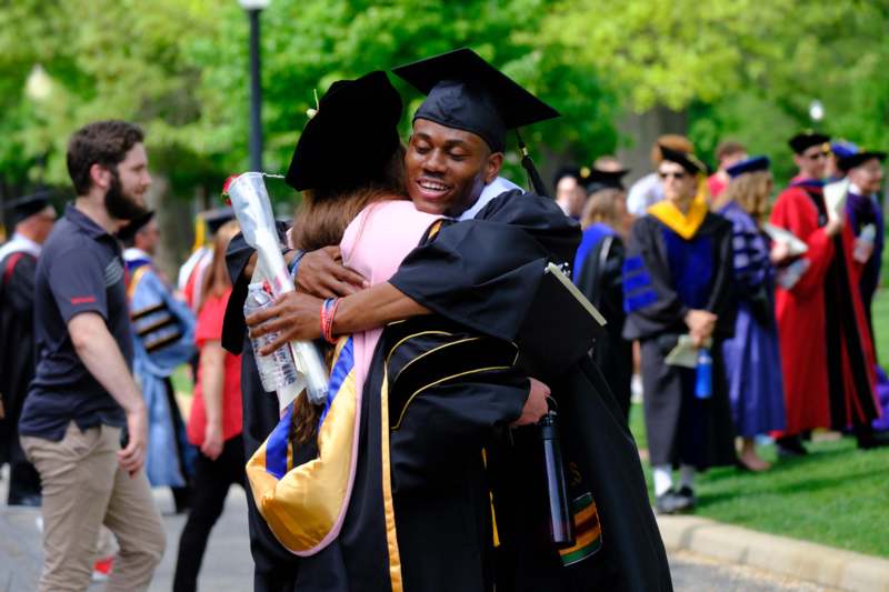 a man in cap and gown hugging a woman