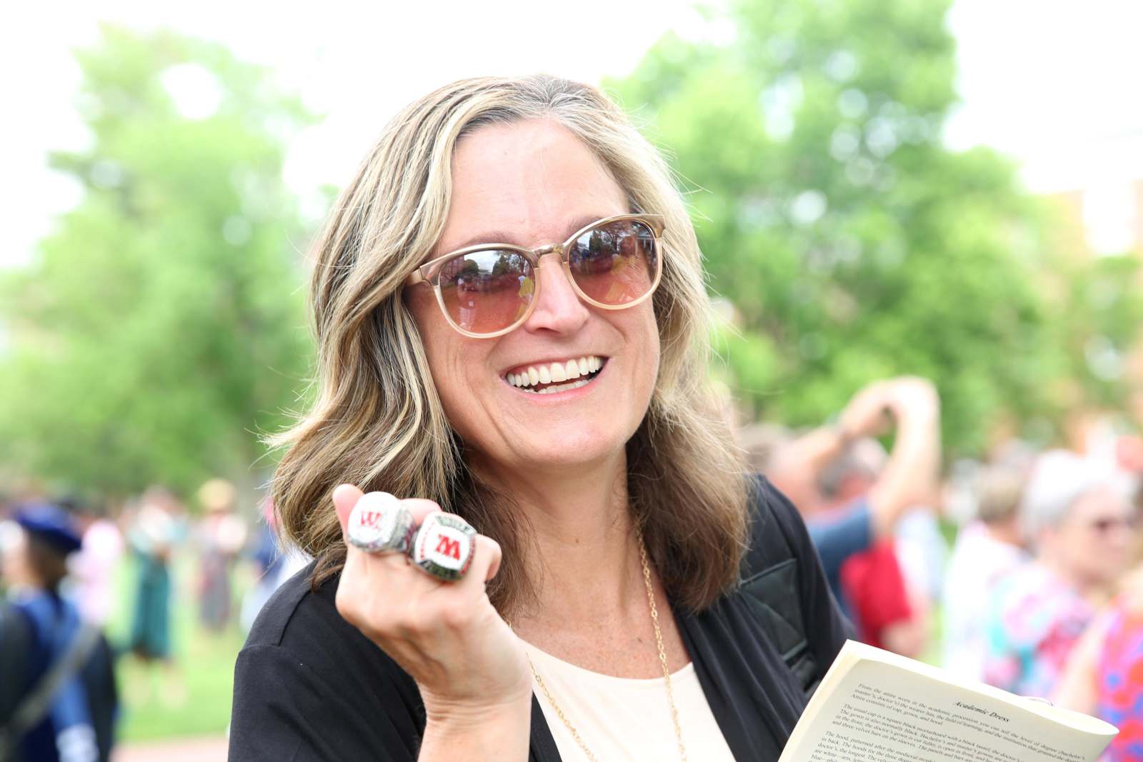 a woman wearing sunglasses and holding two rings