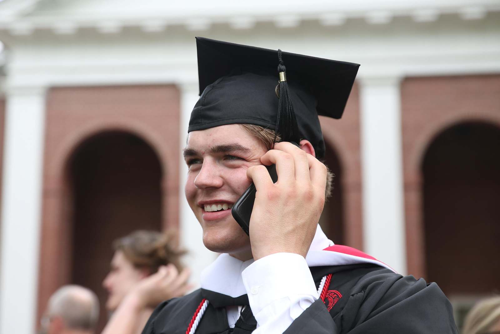 a man in a graduation cap and gown talking on a cell phone