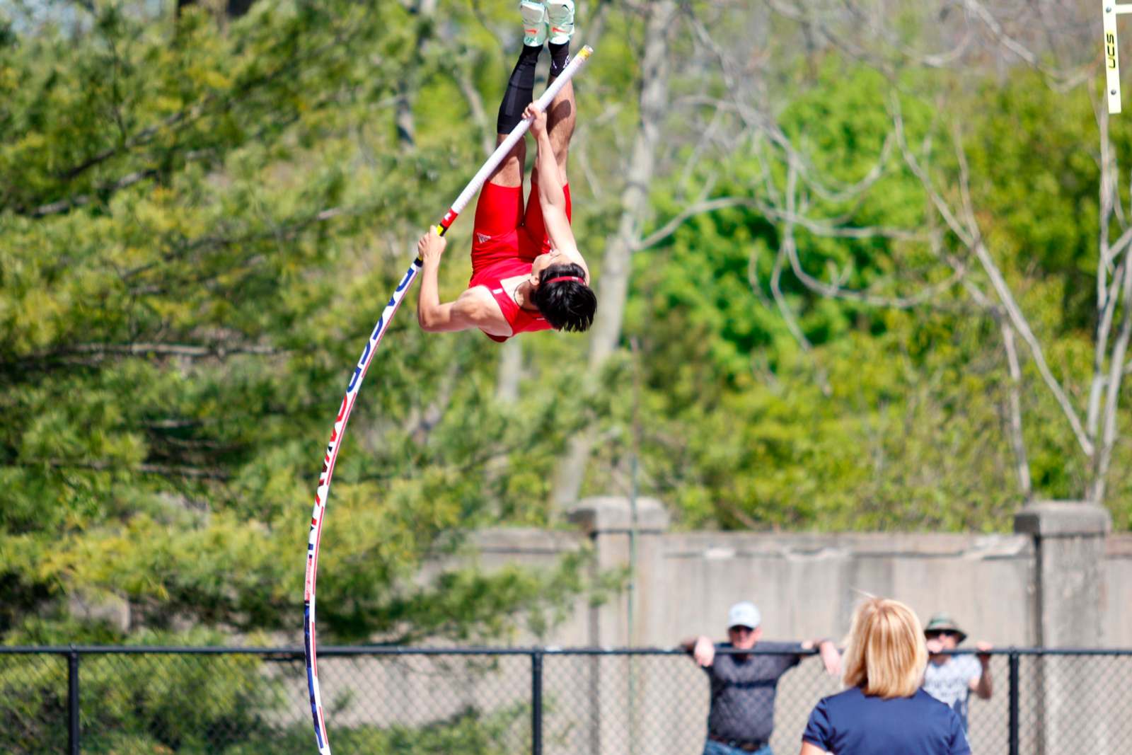 a man in red shirt jumping over a pole