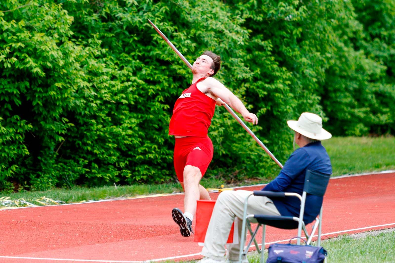 a man in red shorts throwing a pole