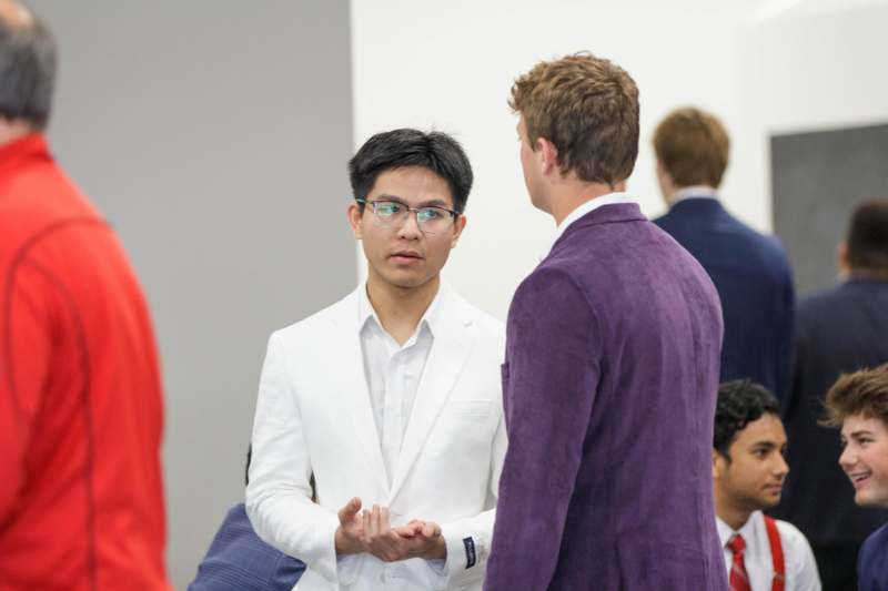 a man in a white suit talking to another man