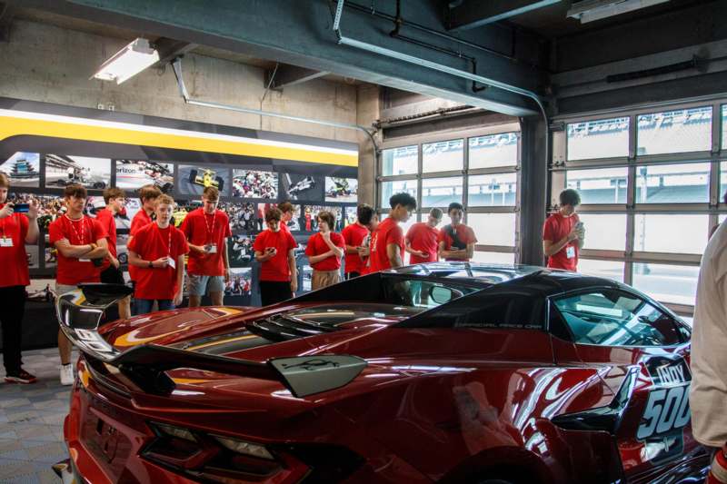 a group of people standing around a red sports car