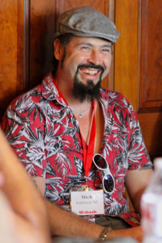 a man wearing a hat and lanyard smiling
