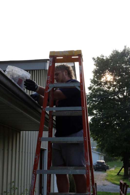 a man on a ladder painting a roof