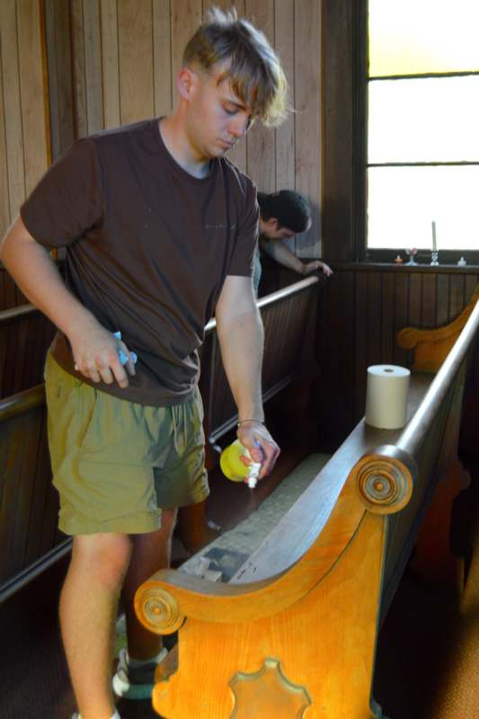 a man spraying a spray bottle on a wooden bench