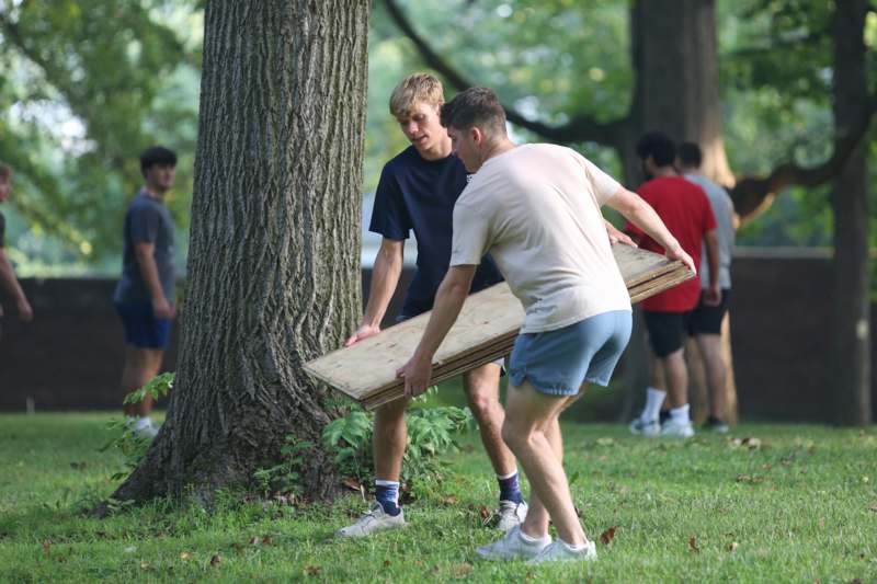 a group of men carrying a wood plank