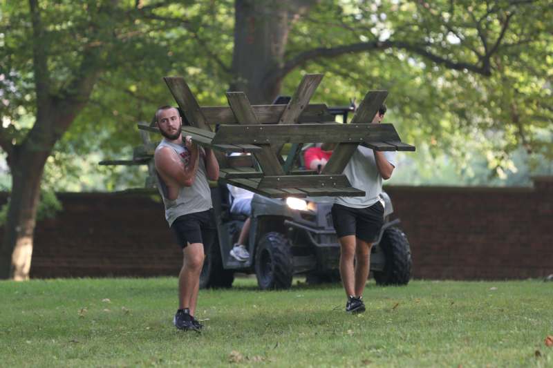 two men carrying a picnic table